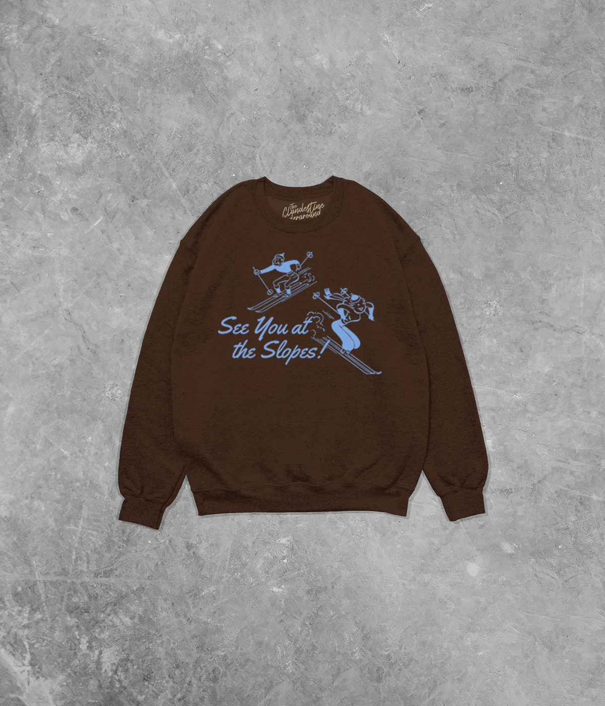 Brown sweatshirt with blue graphic and text on a gray concrete background