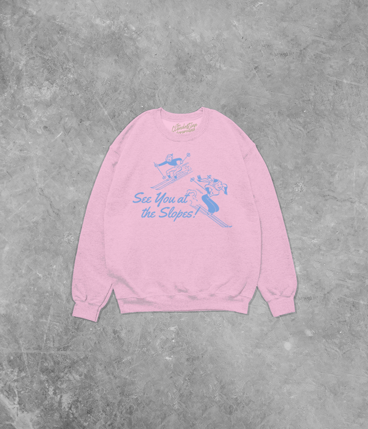 Pink sweatshirt with blue graphic and text on a gray concrete background