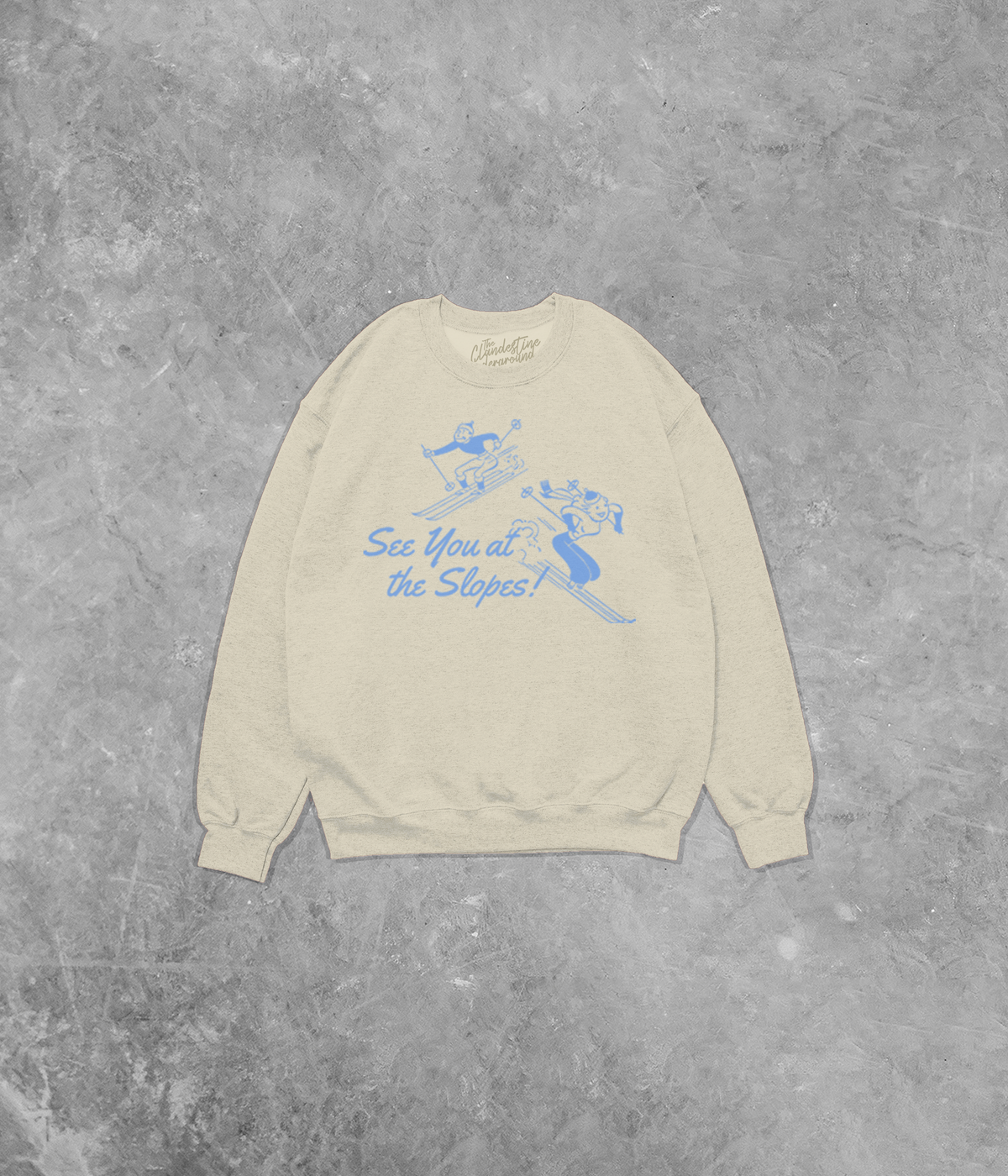 Beige sweatshirt with blue graphic and text on a gray concrete background
